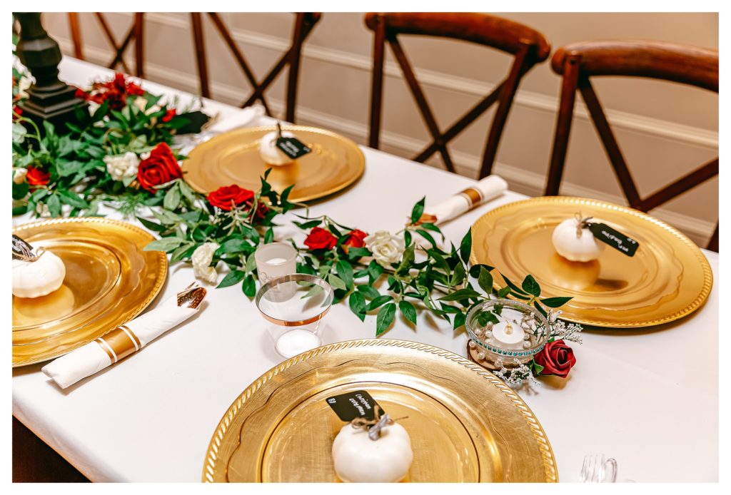 reception decor gold plates and mini pumpkins red roses and greenery
