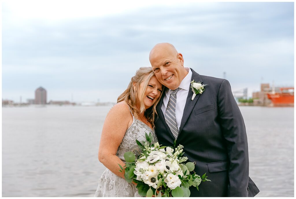 NYC bride and groom posing for portrait with harbor in background