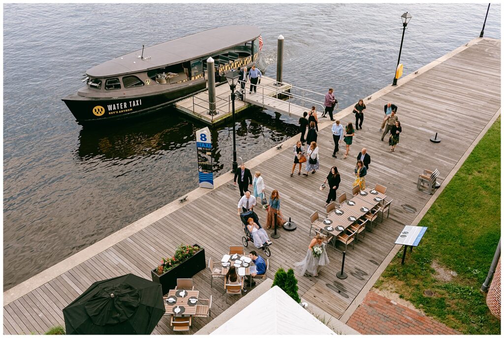 water taxi cocktail hour ends and boat parks by the dock of the harbor as guests exit and head to the reception for wedding of NY couple bride and groom