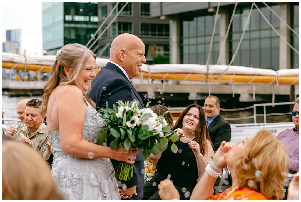 side view of New York city couple walking down aisle on dock by harbor by the water