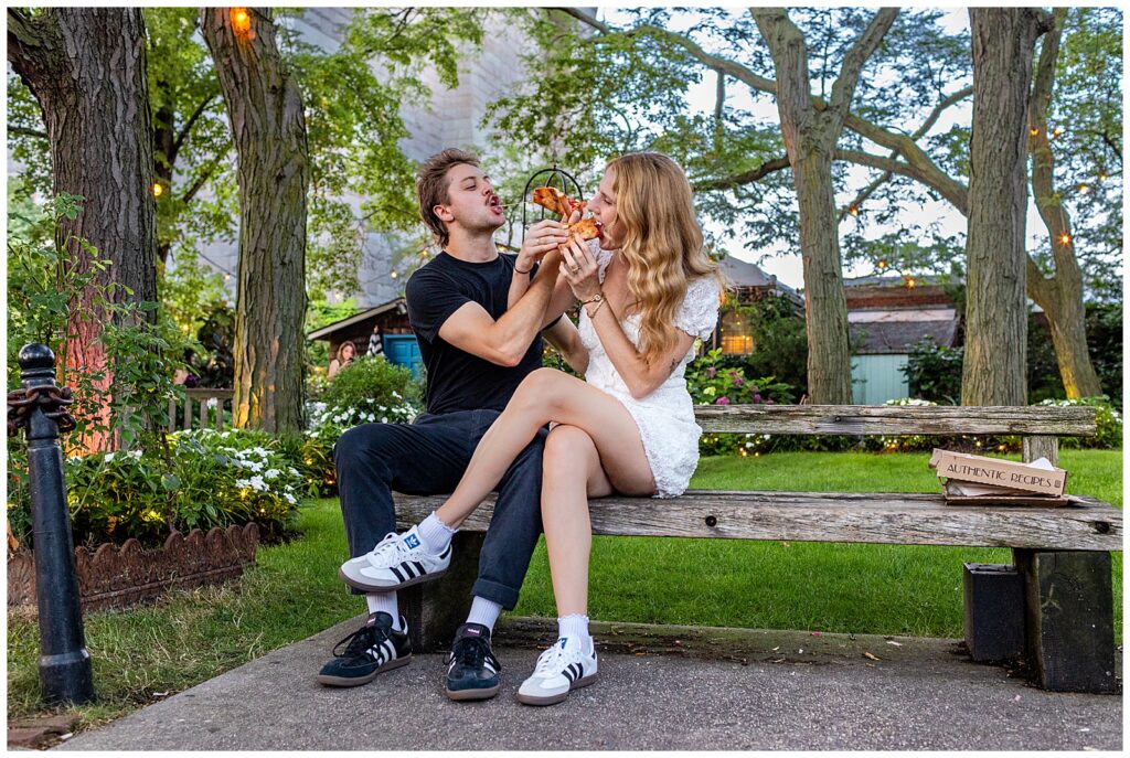 couple in Brooklyn New York eats pizza together during their engagement session in Jardin River Garden near the Brooklyn Bridge