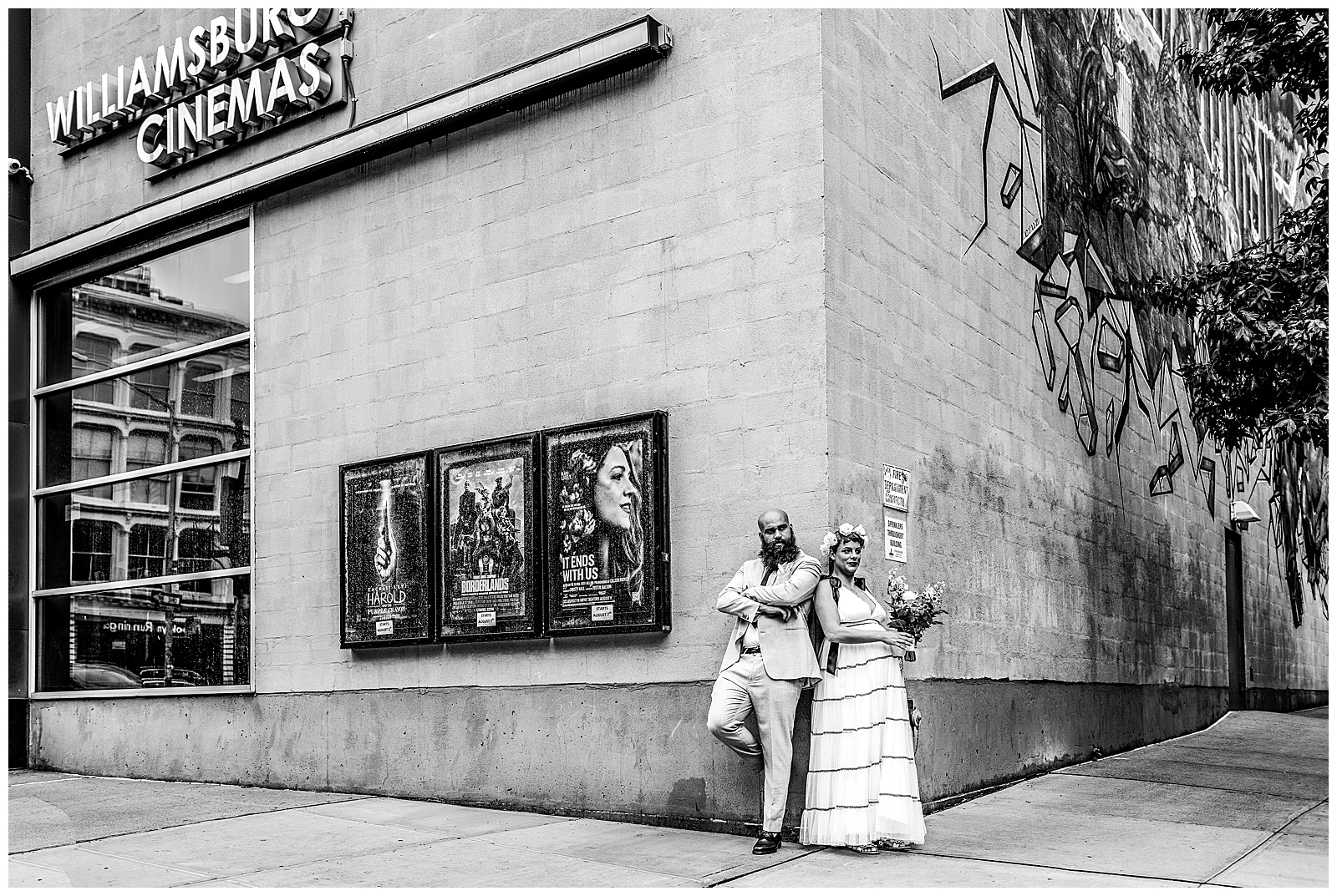 couple poses for wedding day portraits outside of Williamsburg Cinemas