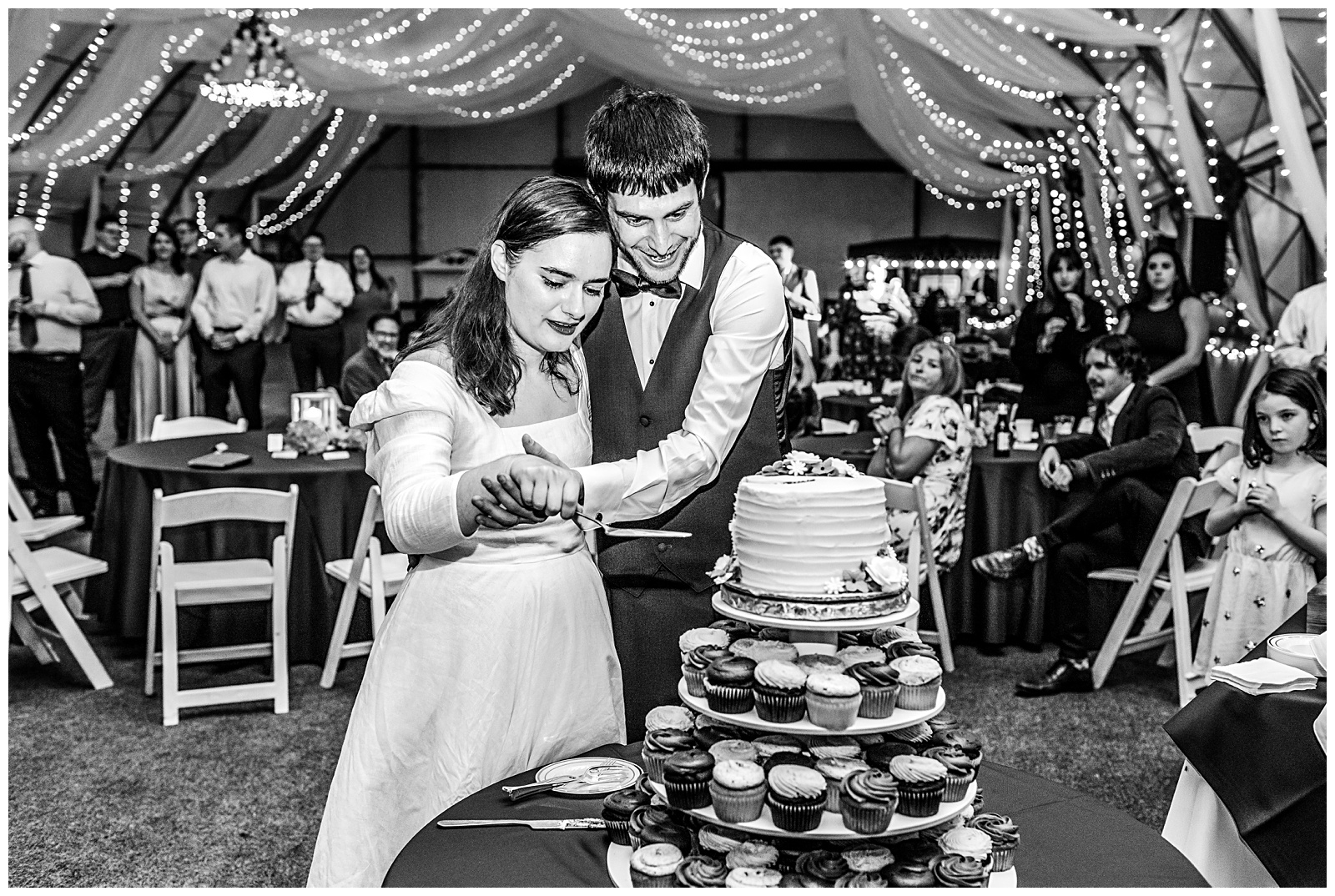 black and white candid of wedding couple cutting cake together