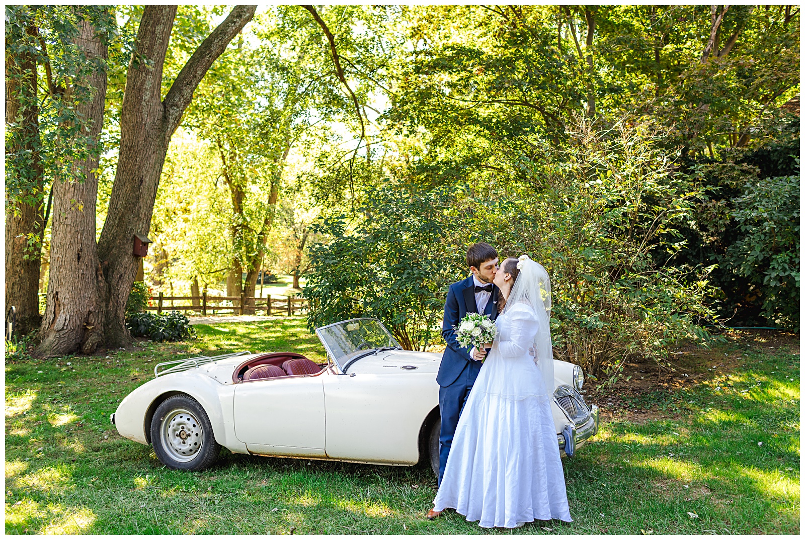 portrait of bride and groom kissing by antique car