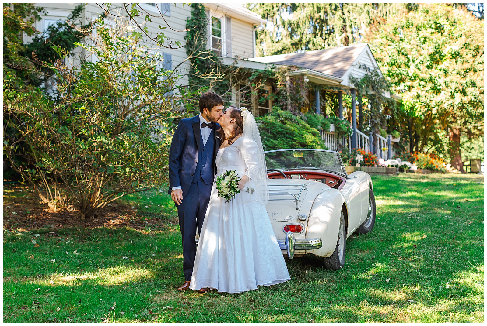 kissing photo of bride and groom in front of unique vintage car during October wedding