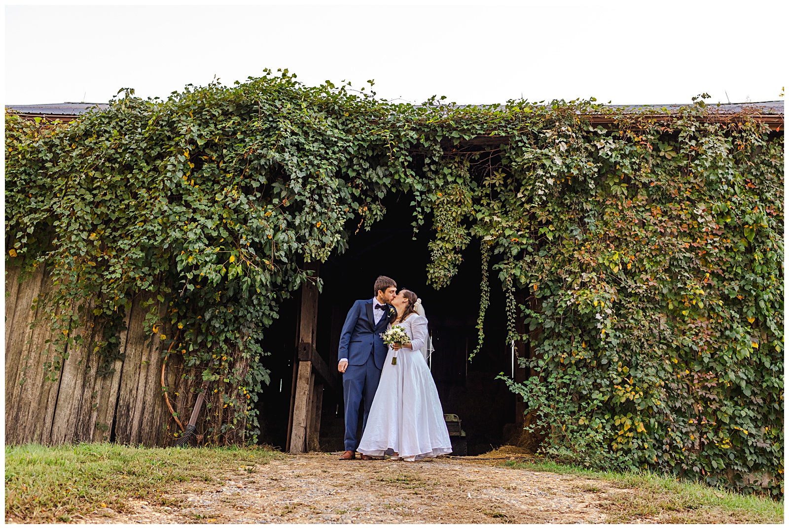 bride and groom kissing on at barn door opening on autumn day