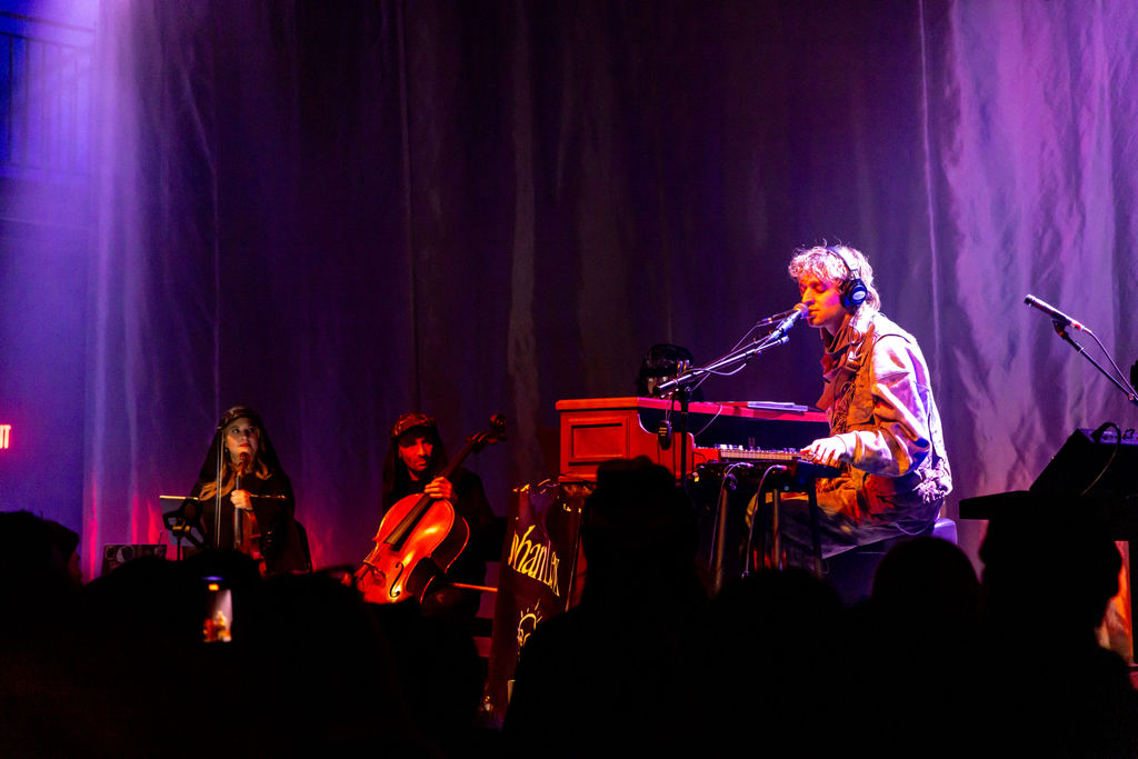Haunting live performance art image of a cellist on stage with 070 Shake at the 9:30 Club in Washington DC, adding cinematic tension to the artist spotlight narrative.