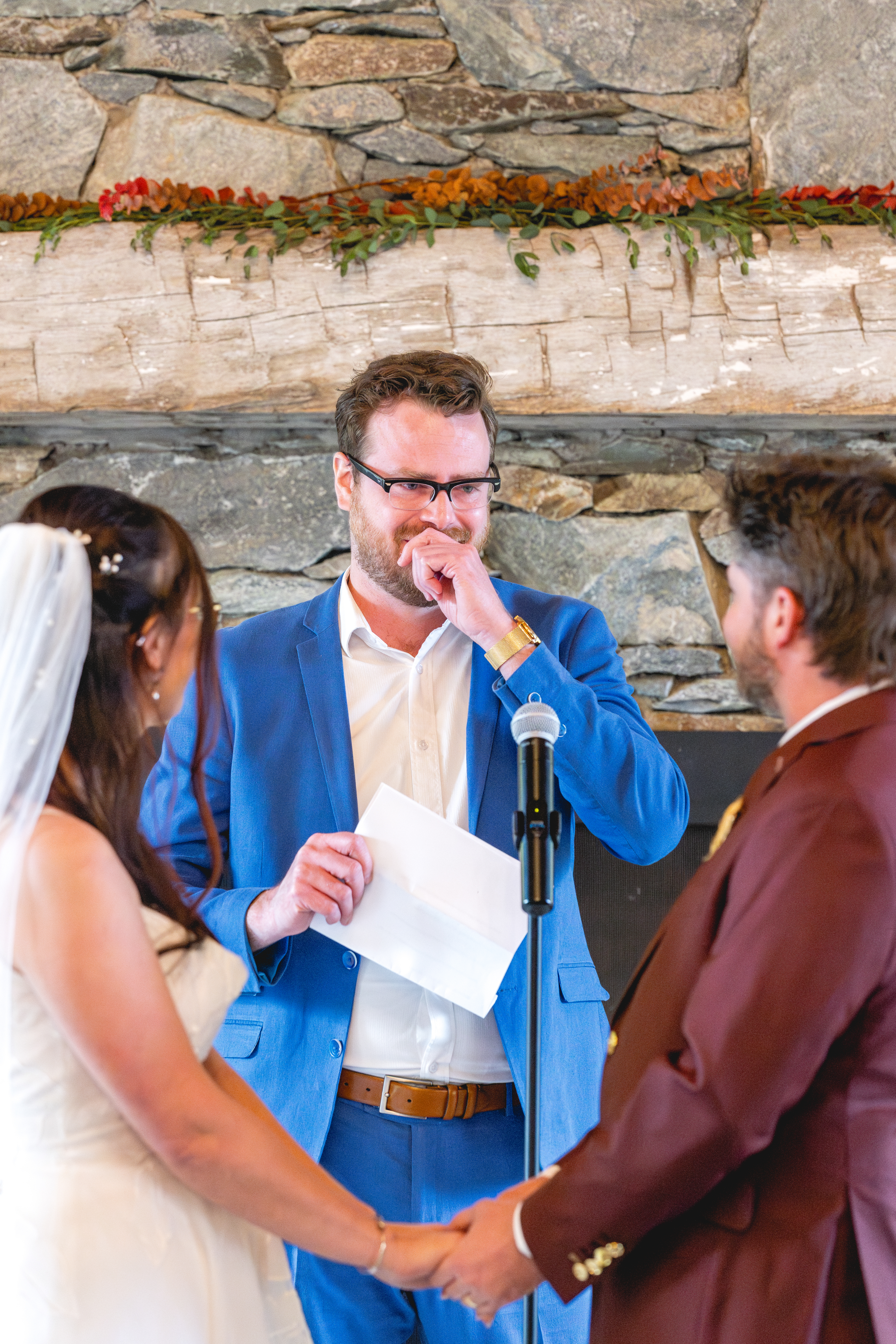 Emotional ceremony moment during an Annapolis Maritime Museum & Park wedding as the couple holds hands while their officiant speaks in front of a stone fireplace