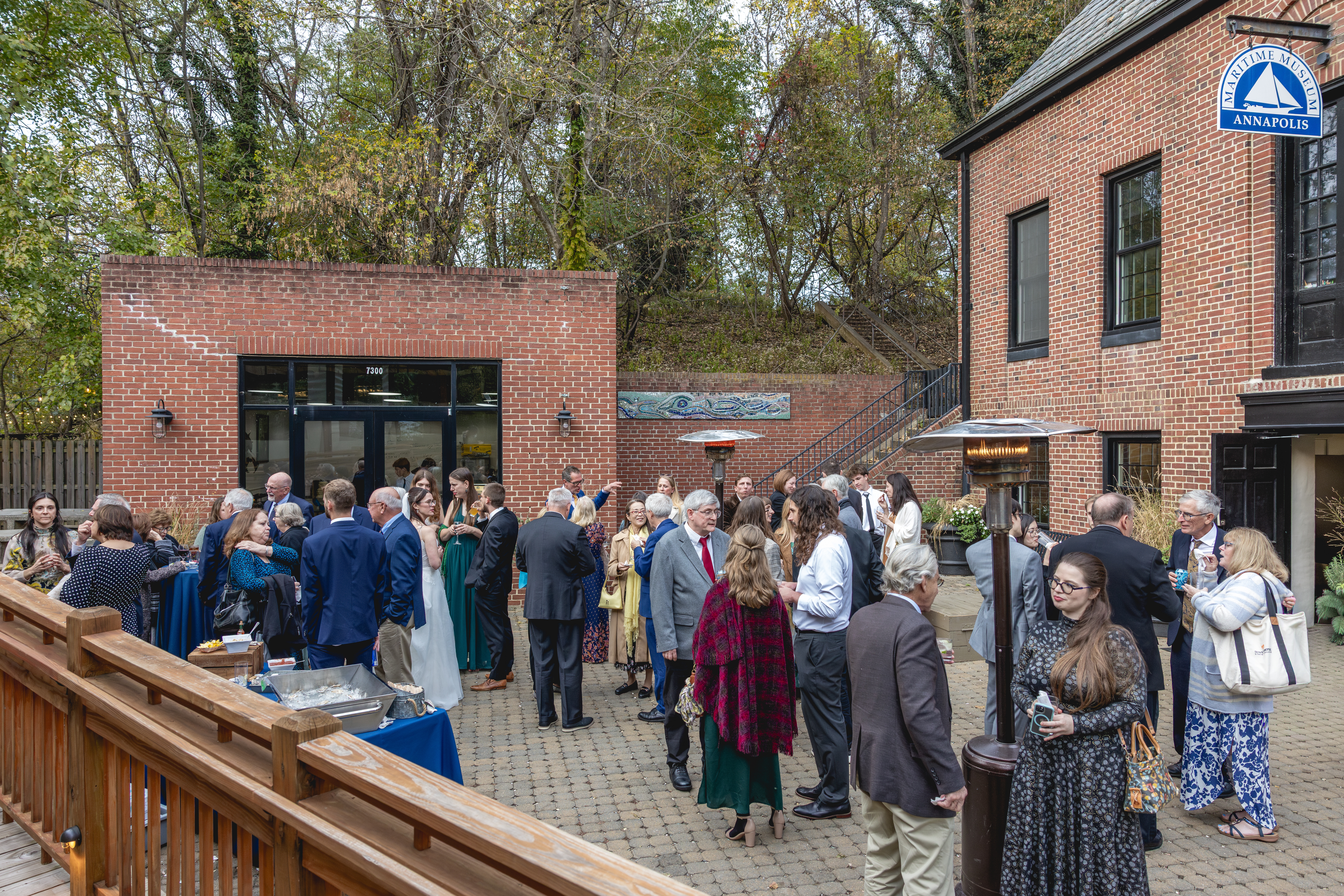 Wedding guests gathering outside brick building with heaters during fall cocktail hour in Annapolis, Maryland