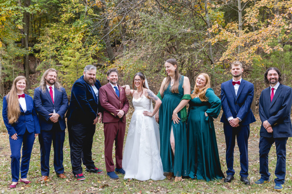 Wedding party group portrait with bride and groom centered and attendants in green dresses and navy suits outdoors in Annapolis, Maryland