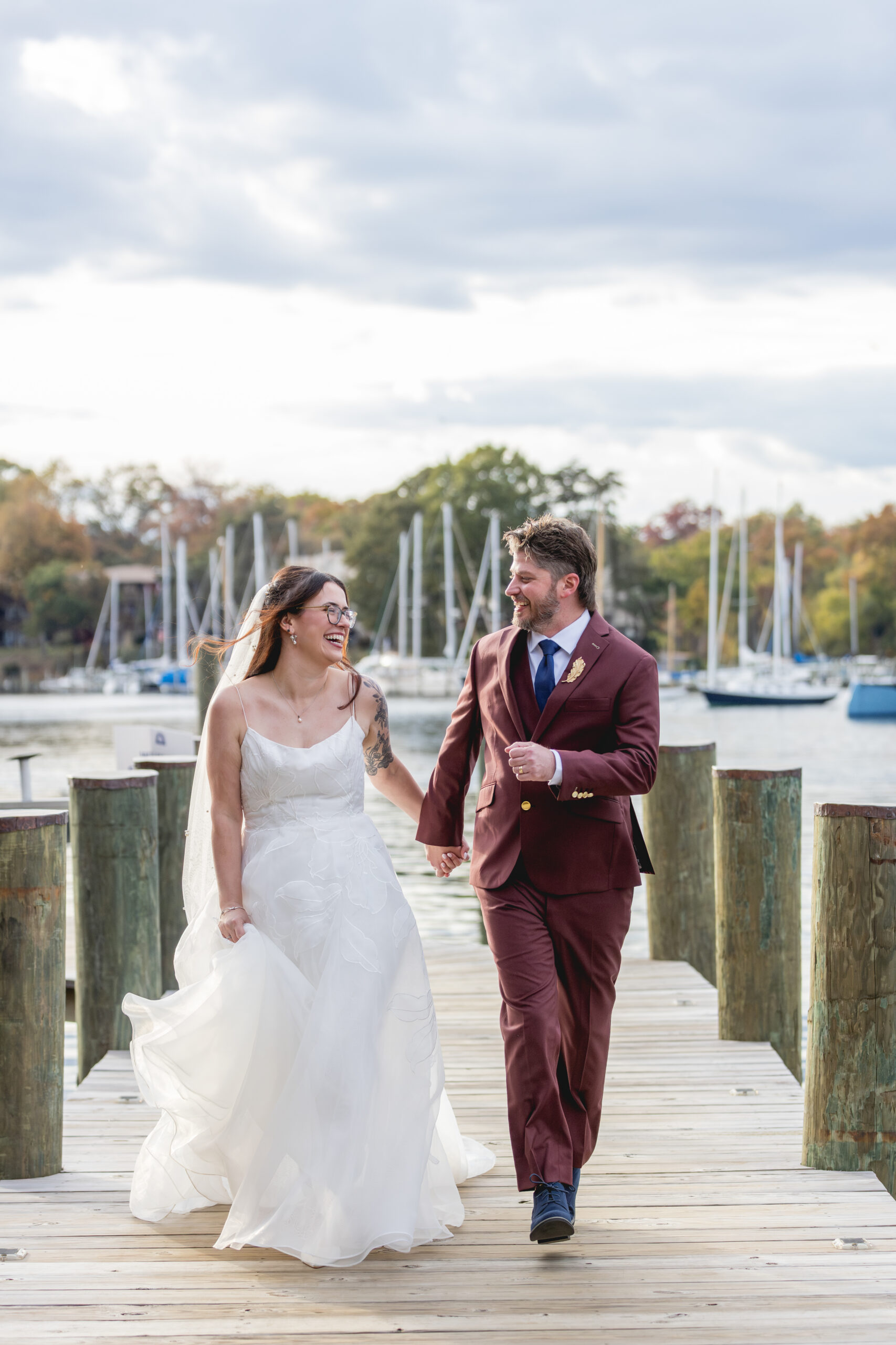Bride and groom walking hand in hand on the dock during their Annapolis Maritime Museum & Park wedding in Annapolis, Maryland
