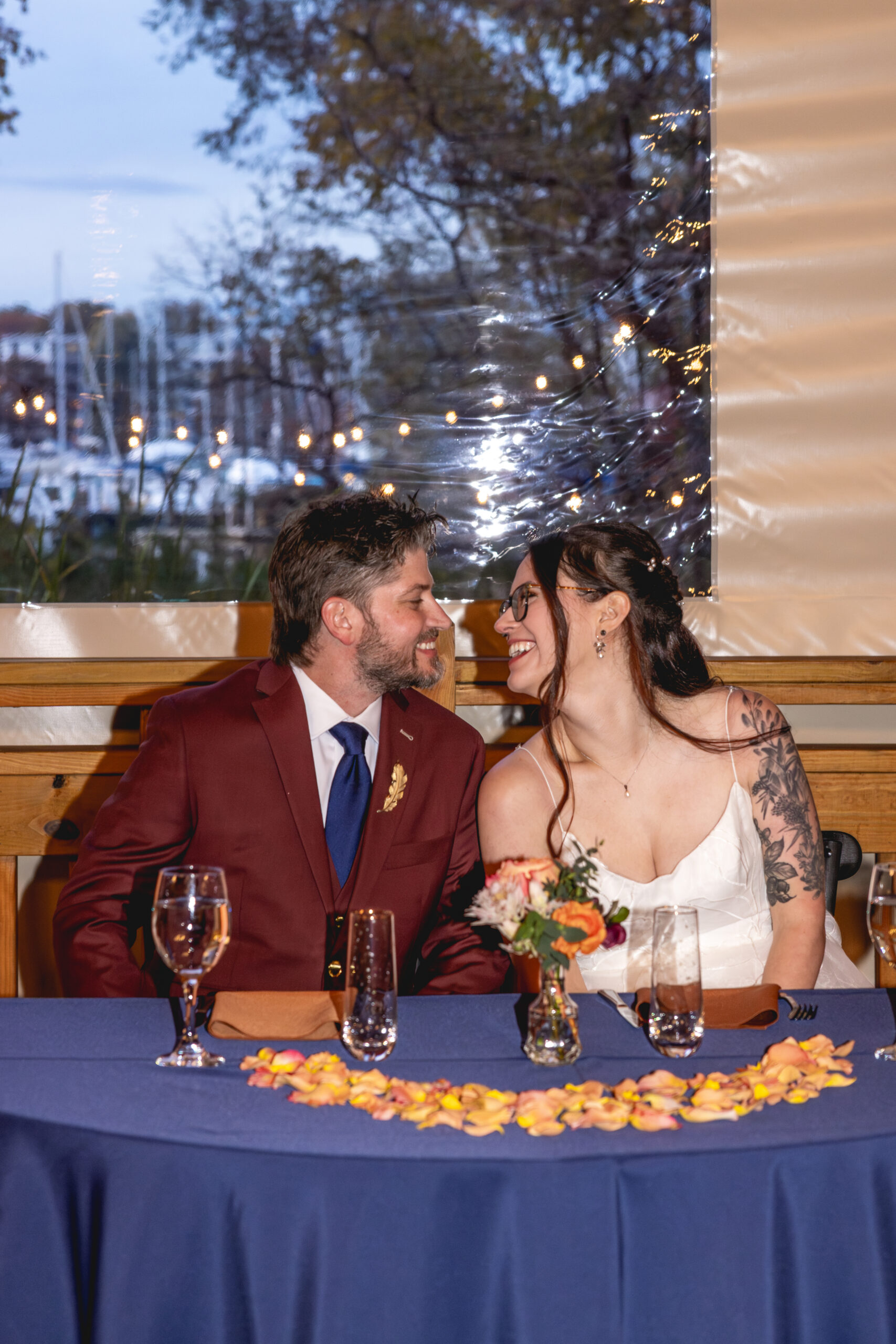 Bride and groom smiling at each other at their sweetheart table during an Annapolis Maritime Museum & Park wedding
