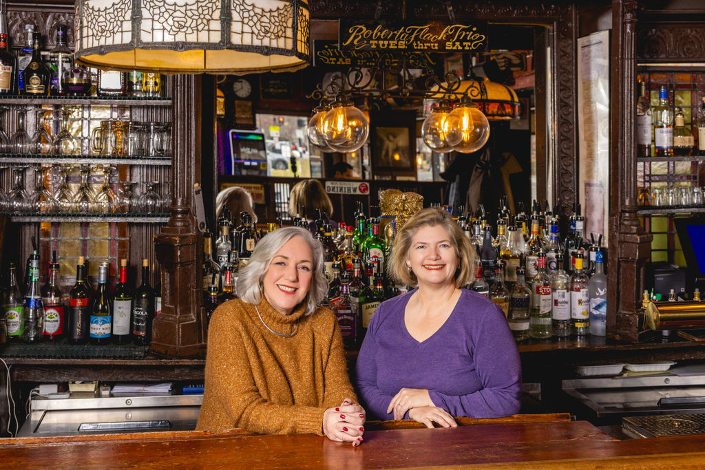 two women seated at bar inside historic restaurant for commercial branding imagery