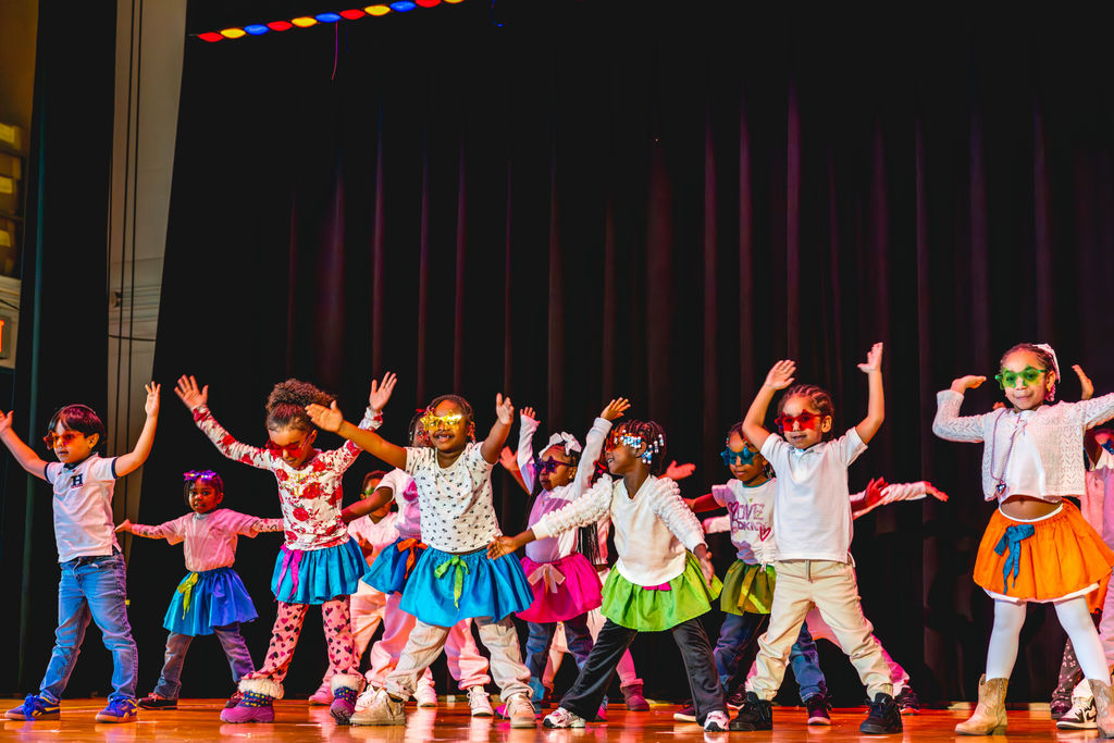 Children performing on stage in colorful costumes at P.S. 272 Curtis Estabrook after-school event