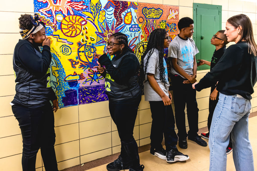 Documentary school photography of students collaborating by colorful mural in New York