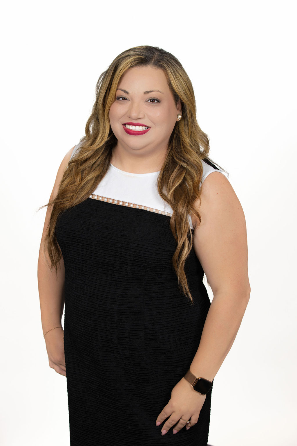 Standing corporate headshot of a woman with long wavy honey-blonde hair wearing a black and white dress, photographed on a white background by Liz Stewart Photography DC
